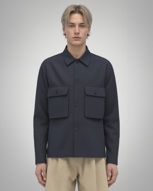 Navy blue cotton twill utility overshirt with a relaxed fit. Features a four-button front closure, two oversized flap pockets, refined topstitching, and a soft matte finish. Fully lined for added structure and durability. Designed for effortless layering and cut and sewn in Australia.