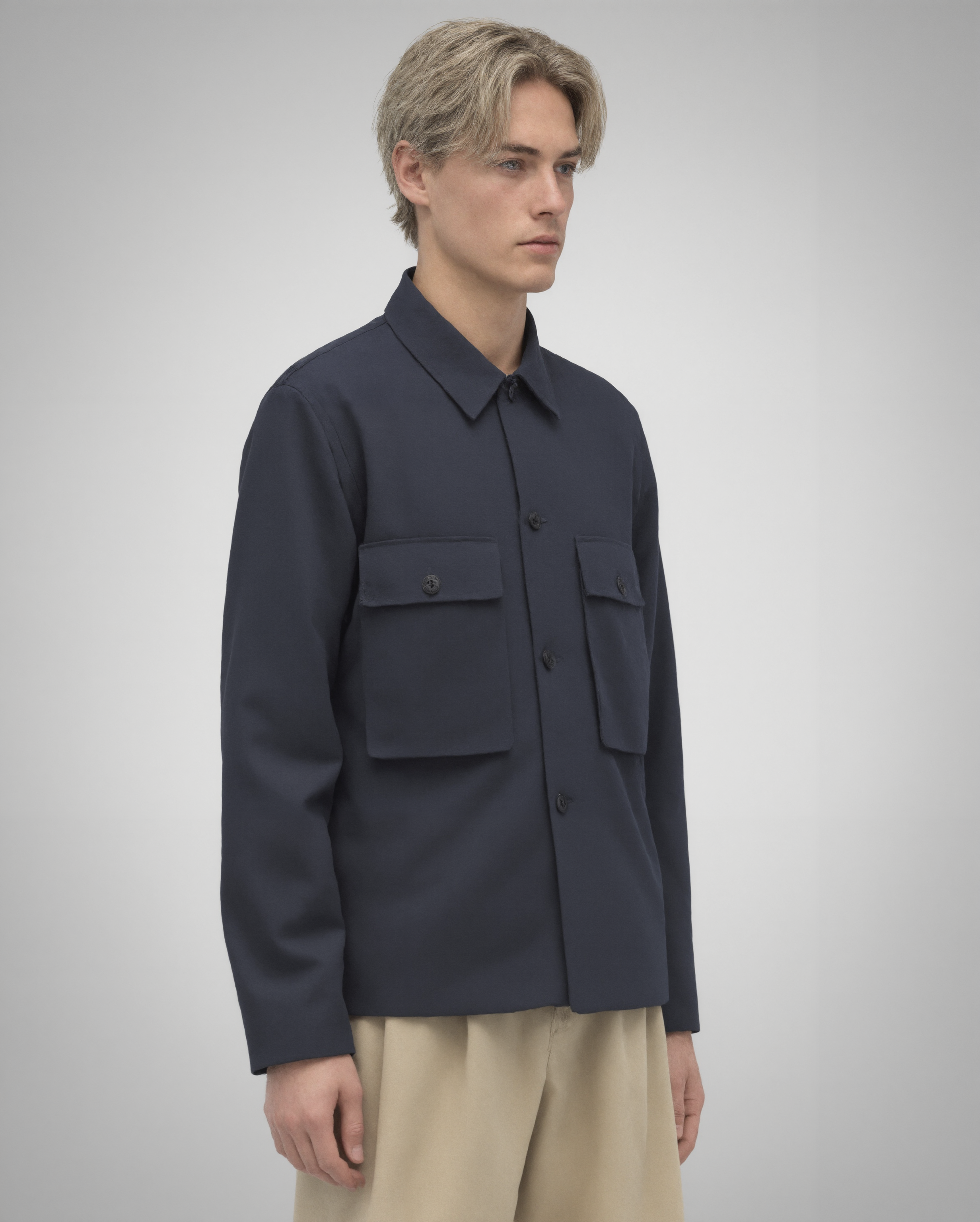 Navy blue cotton twill utility overshirt with a relaxed fit. Features a four-button front closure, two oversized flap pockets, refined topstitching, and a soft matte finish. Fully lined for added structure and durability. Designed for effortless layering and cut and sewn in Australia.